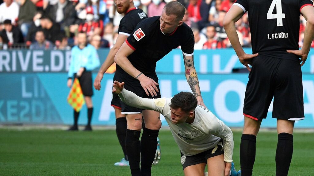 florian wirtz de joelho no gramado sendo socorrido pelo juiz 