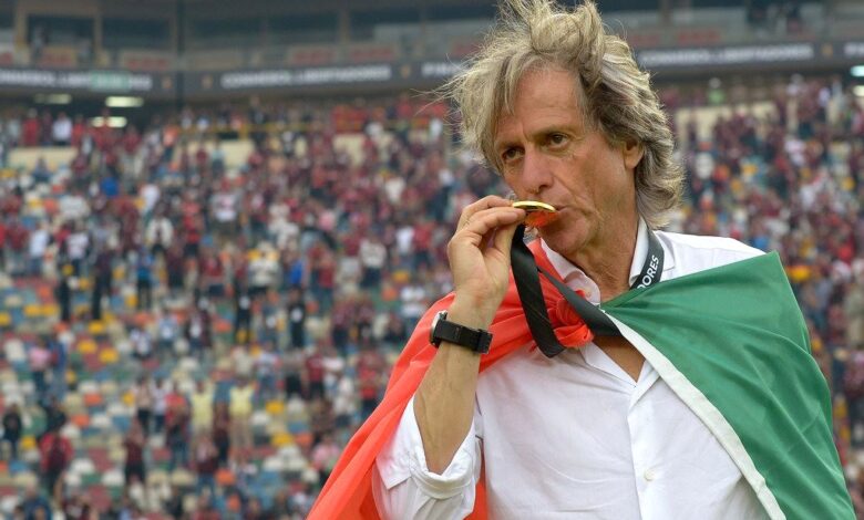 jorge jesus beija a medalha da libertadores coberto pela bandeira de portugal