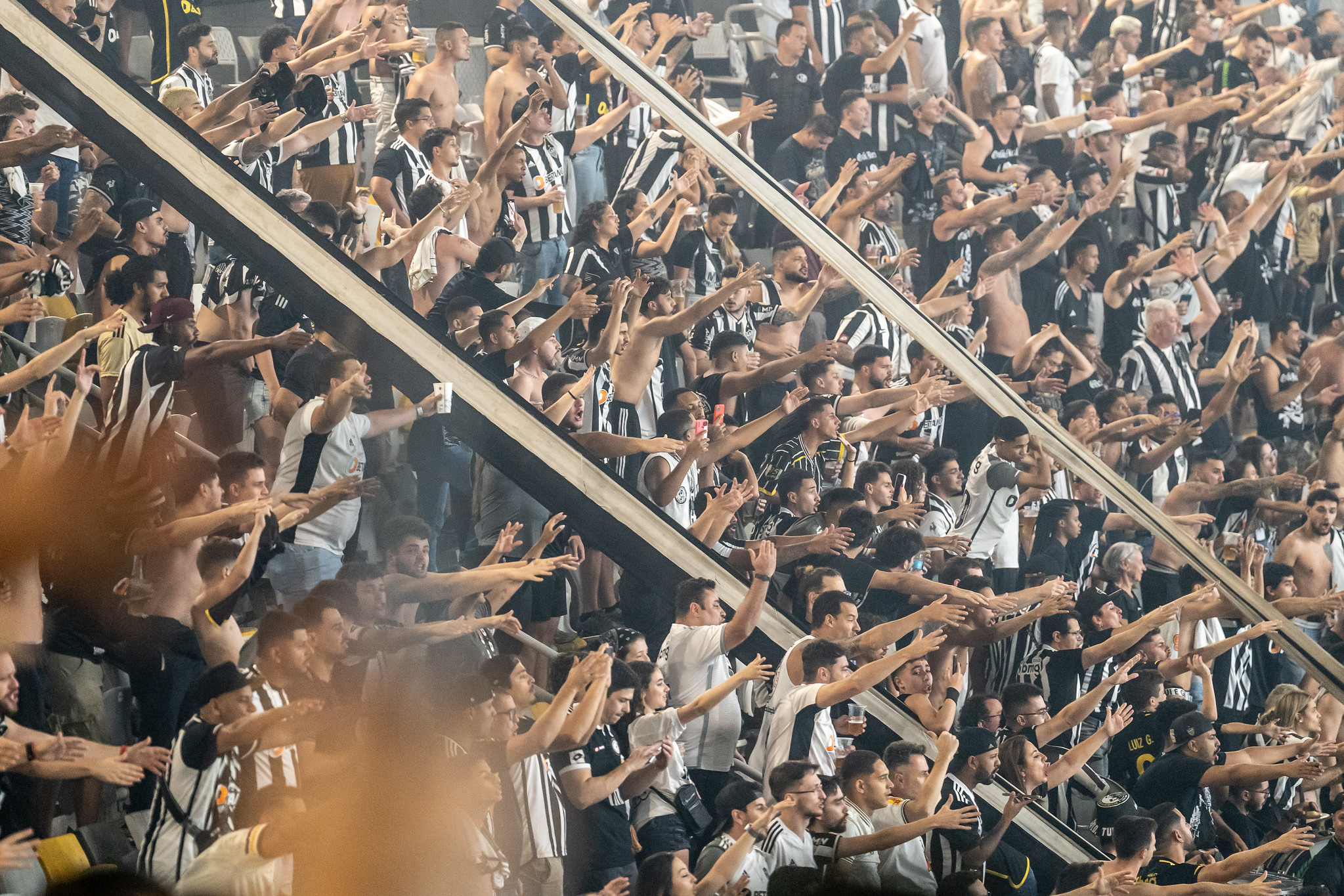 torcida do atlético mineiro em meio a faixas preto e brancos torcendo para a equipe