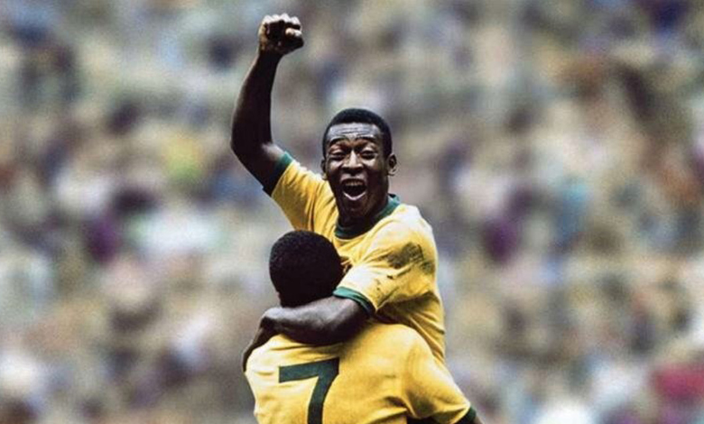 Na foto está o mineiro Pelé, um jogador negro que comemora o seu gol com o punho fechado e o braço levantado. Ele está vestido uma camisa amarela e está sendo segurado por Jairzinho, um outro jogador negro que veste uma camisa amarela com o número 7 escrito em verde nas costas.